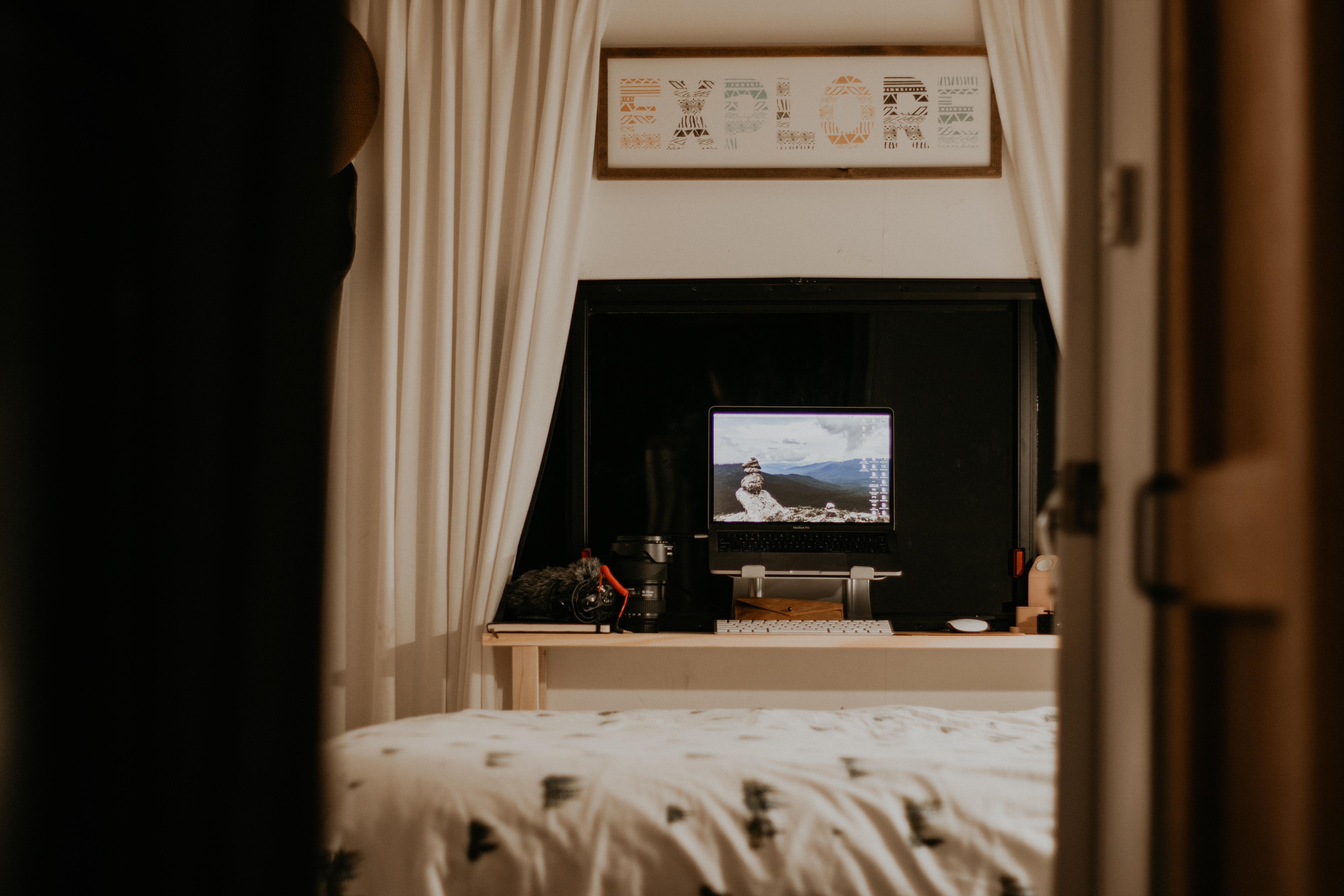 A makeshift desk on a small shelf next to a bed in an RV. 
