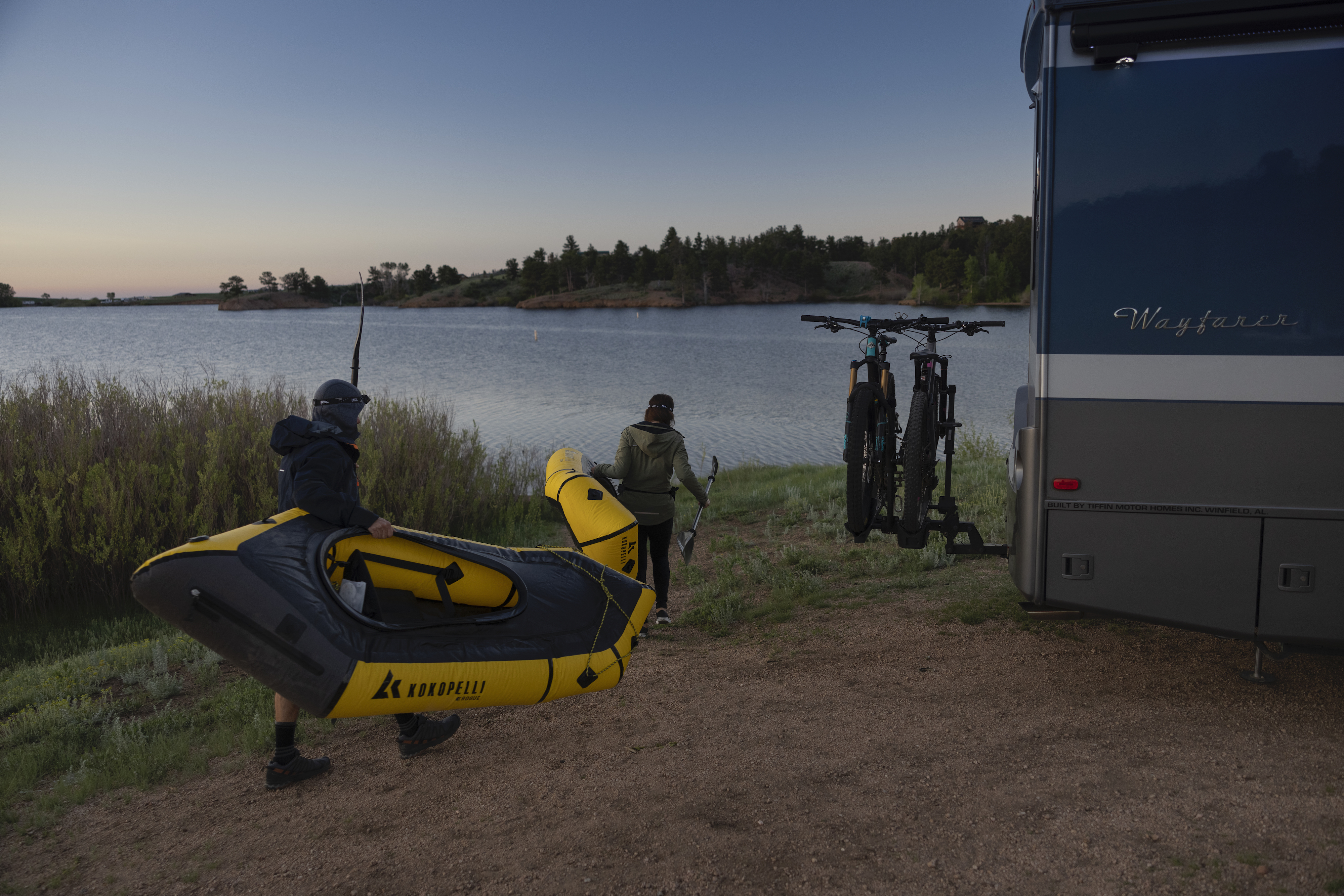 Dustin and Sarah carrying their packrafts to water next to their Tiffin Wayfarer