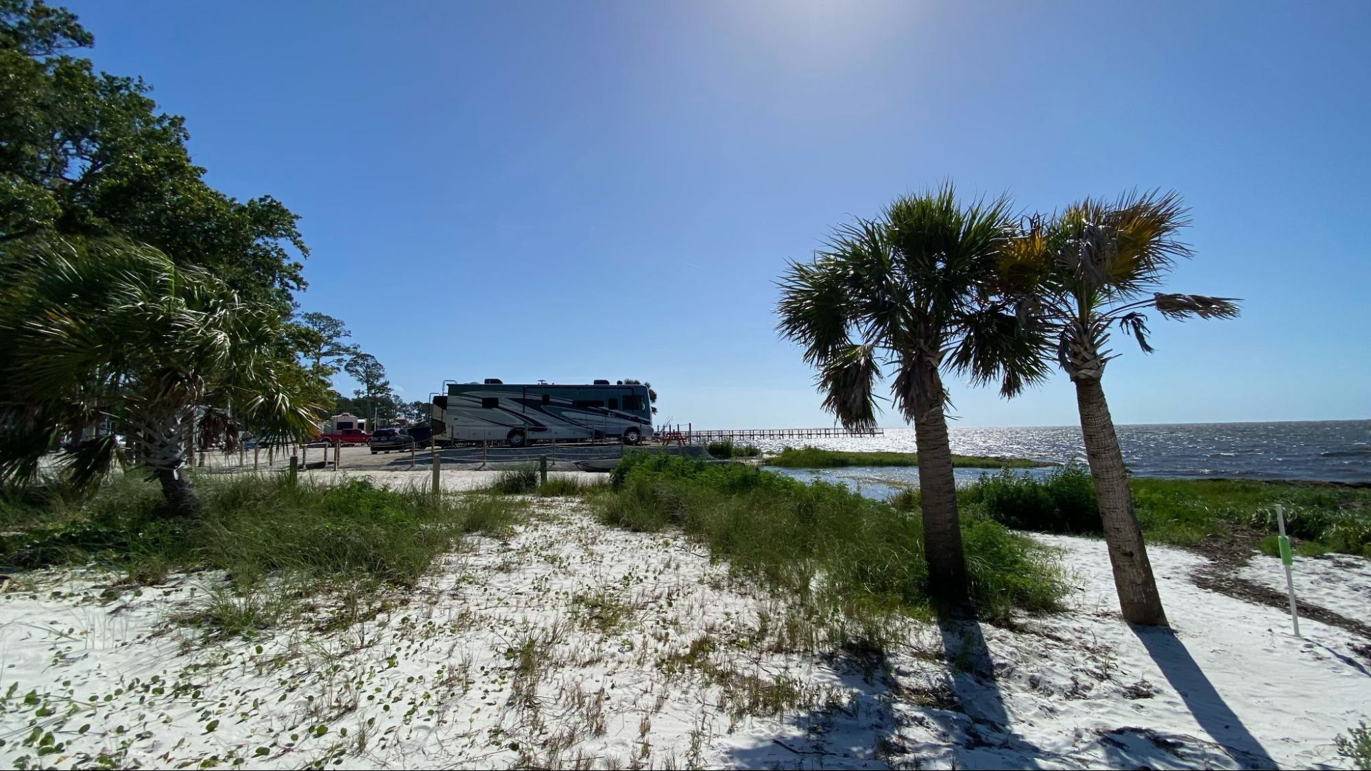 Michael and Tiffany Dunagan's Tiffin Allegro RV parked at a waterfront beach campsite.