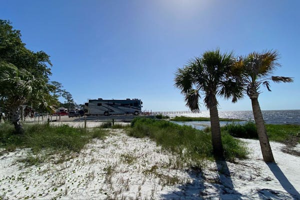 Michael and Tiffany Dunagan's Tiffin Allegro RV parked at a waterfront beach campsite.
