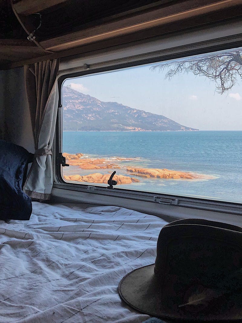 A view from the inside of an RV looking out the window to Coles Bay, in Tasmania, Australia. 