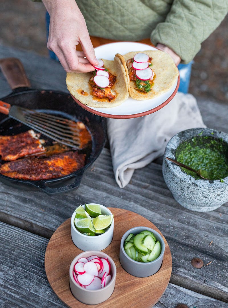Woman adds radishes and other toppings to her tacos.