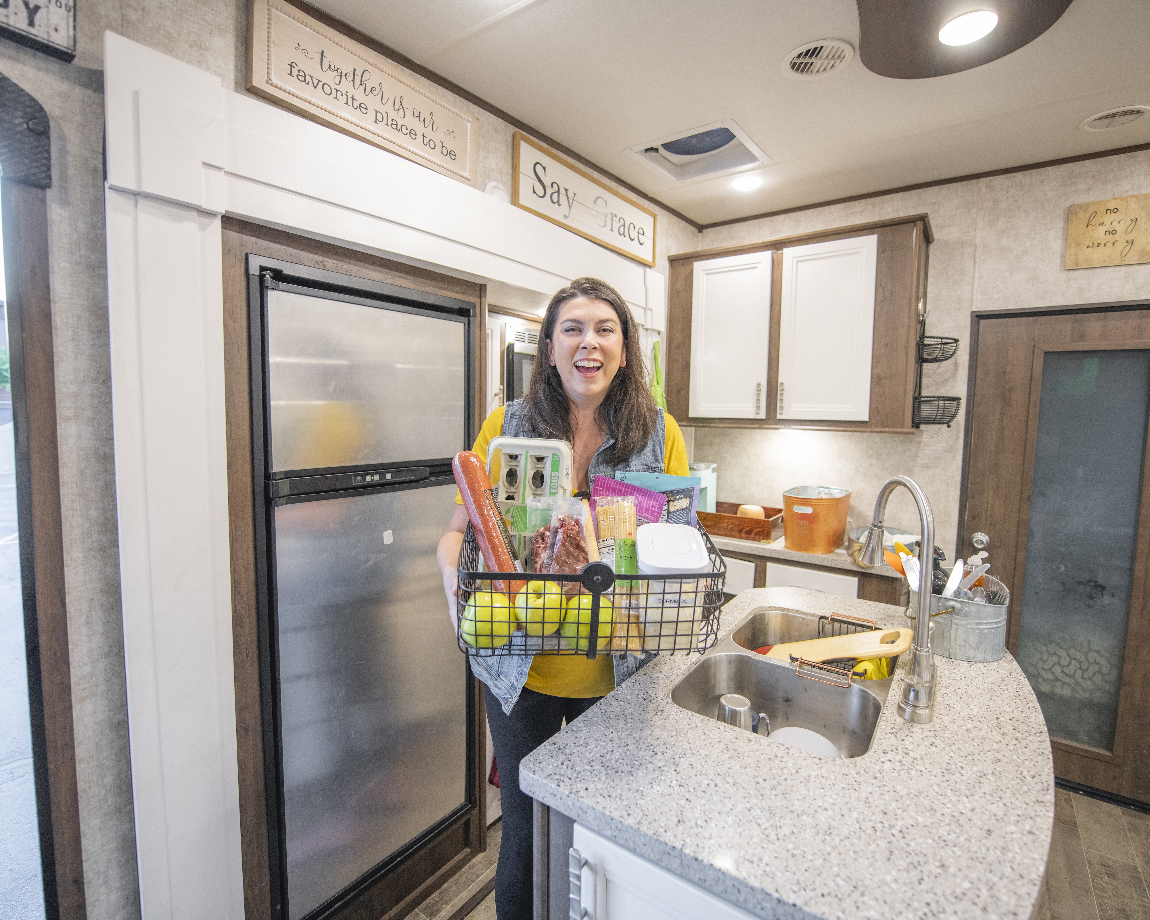 Chelsea Day holding a basket of food in the kitchen of her Highland Ridge RV