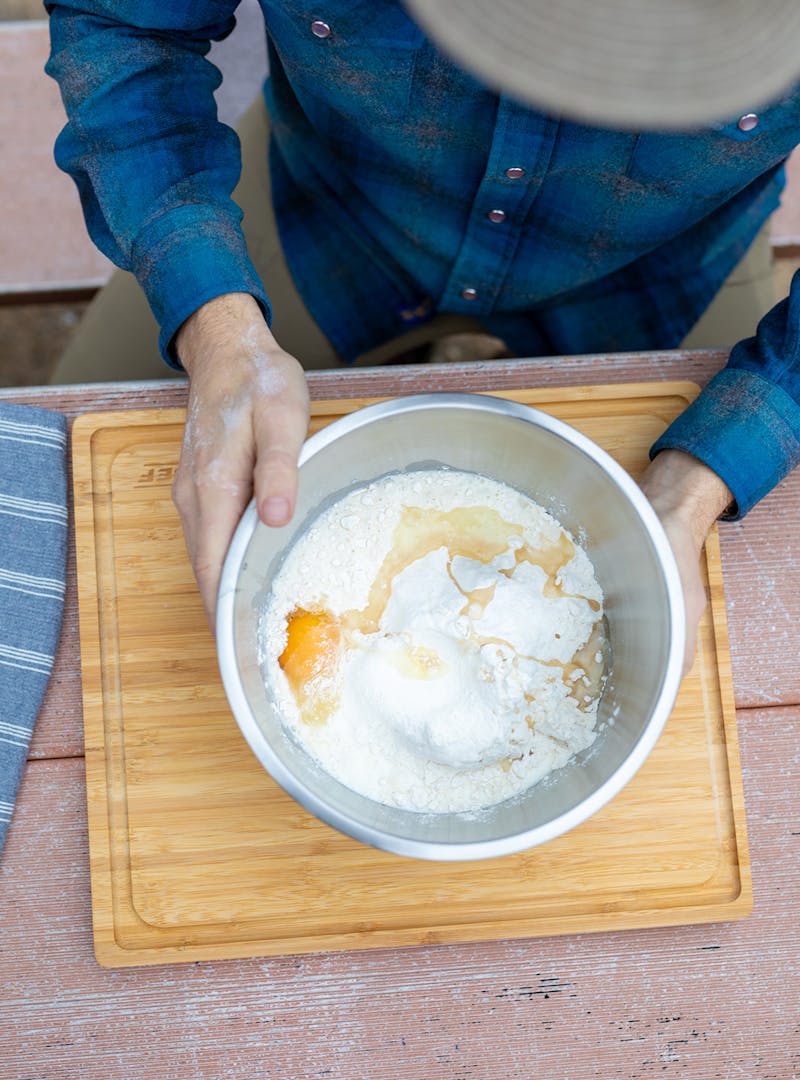 Mixing eggs and flour in a bowl for beignets.