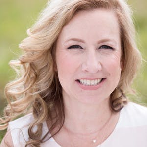 Headshot of Honey Shea, a white woman with curled blonde hair, smiling