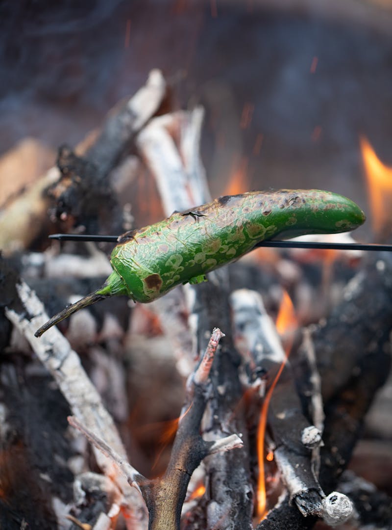 A jalapeño roasting over an open flame.