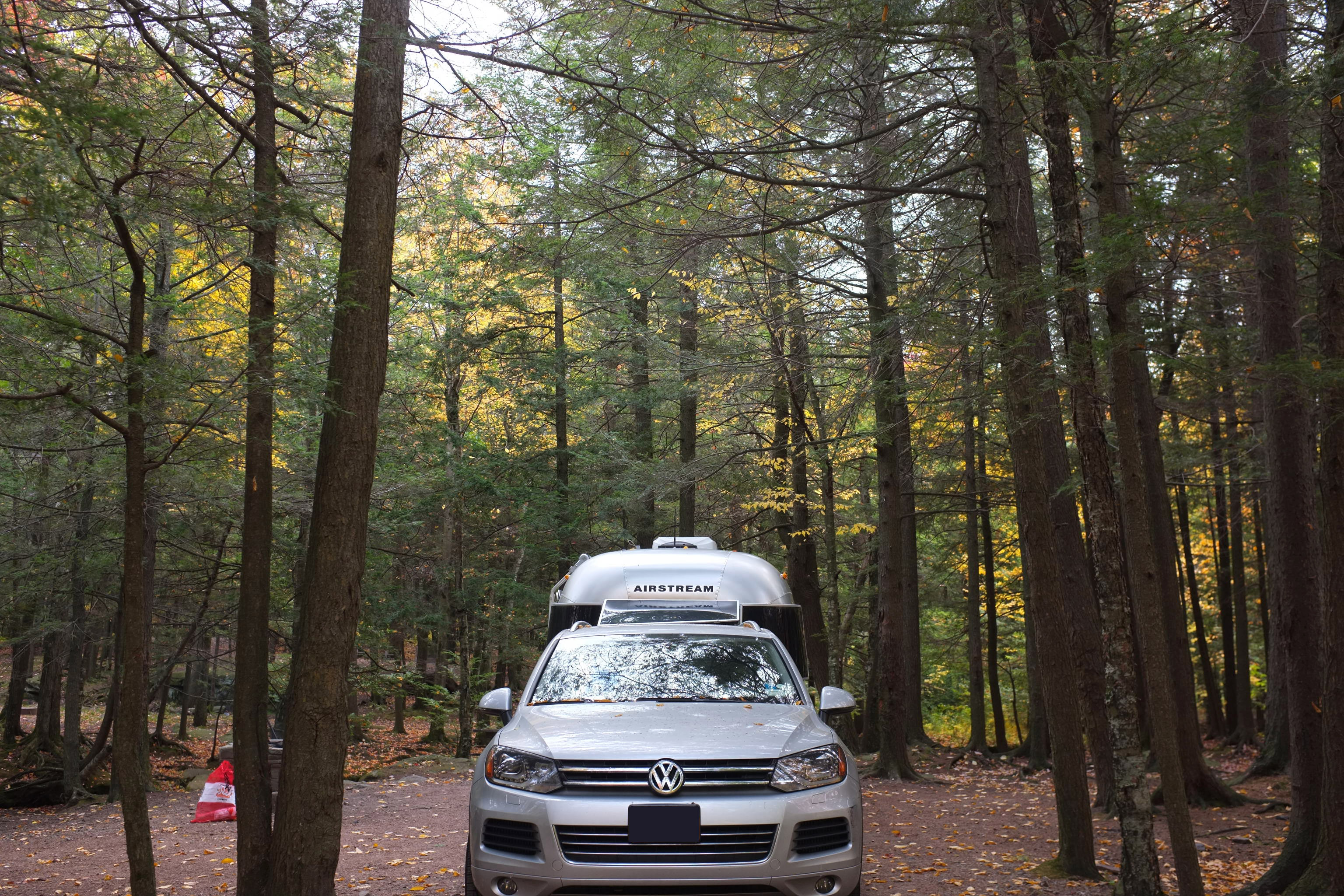 Dr. Na's Airstream and car parked in a wooded campsite.