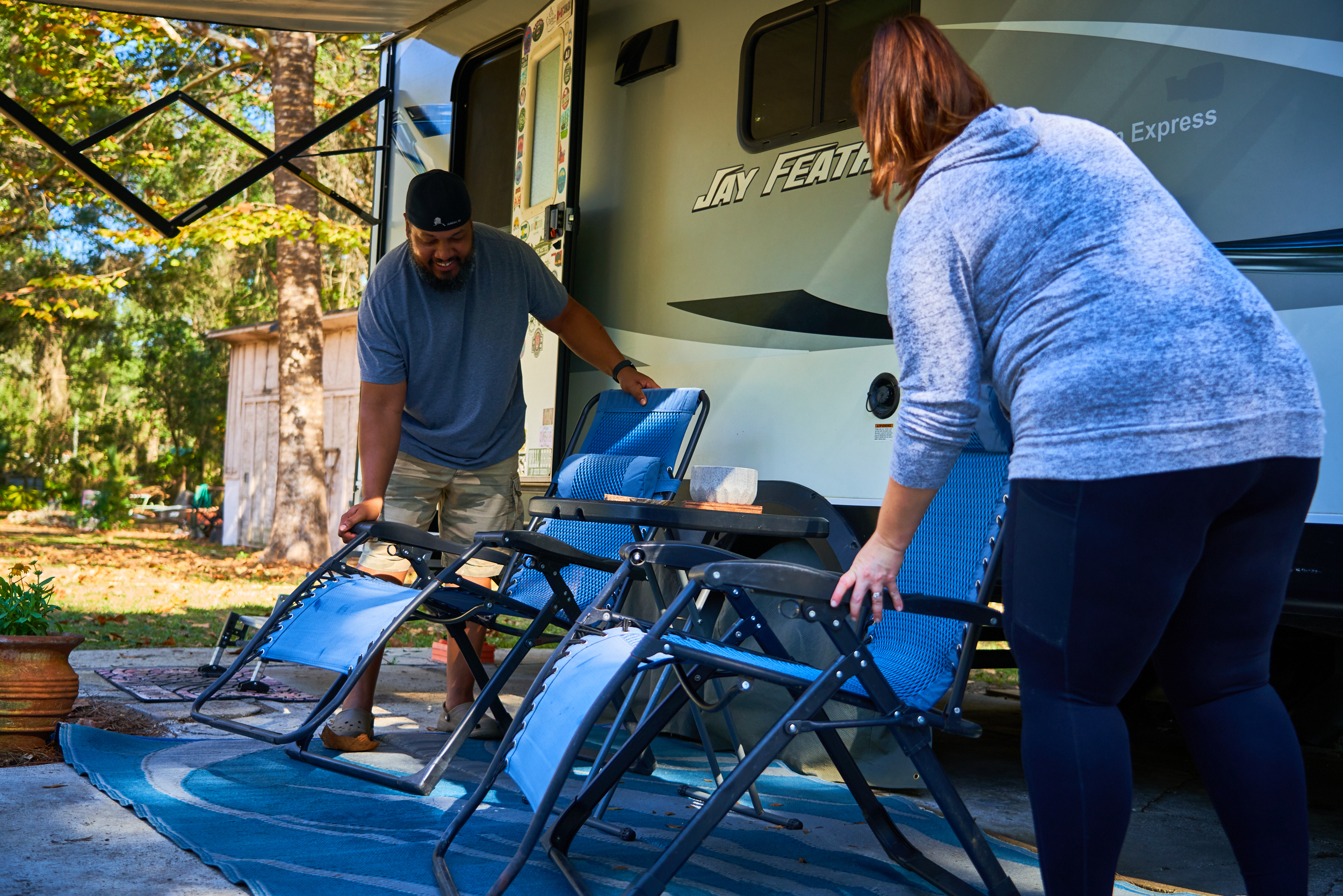 Ben and Christiana McMillan setting out camping chairs in front of their Jay Feather RV
