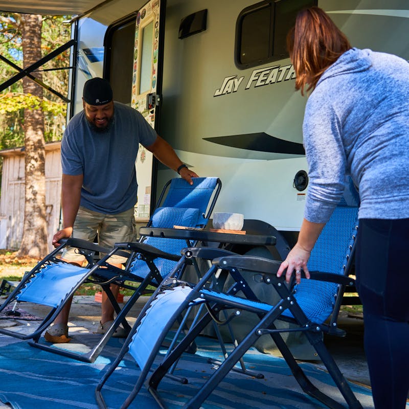 Ben and Christiana McMillan setting out camping chairs in front of their Jay Feather RV