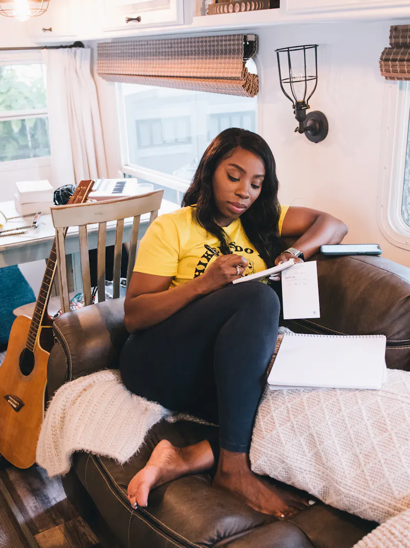 Jessy writes in a notebook on the couch inside her Keystone Couger