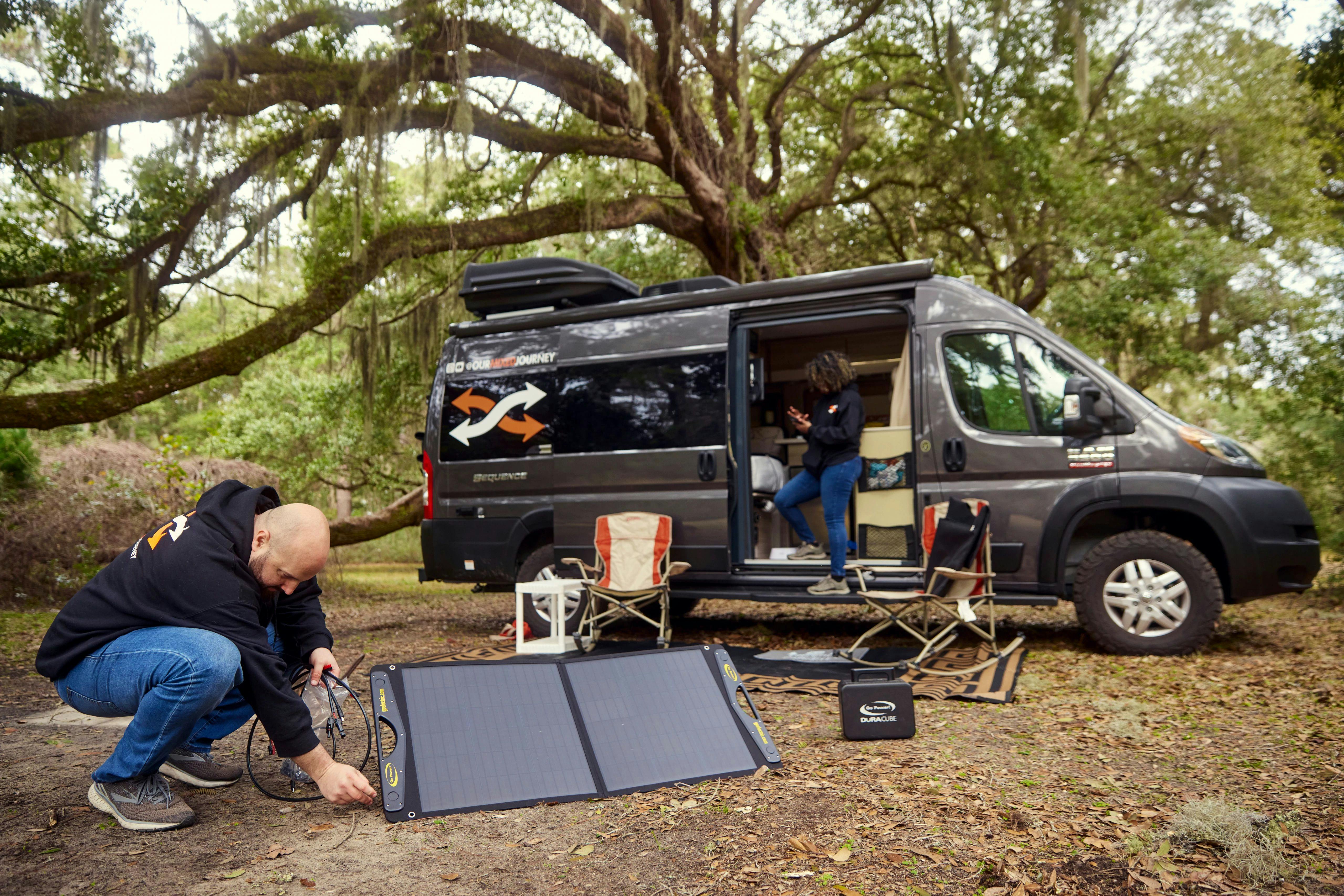 Gabe sets up solar power in front of this thor motor coach sequence while Rocio uses an app on her phone in the doorway