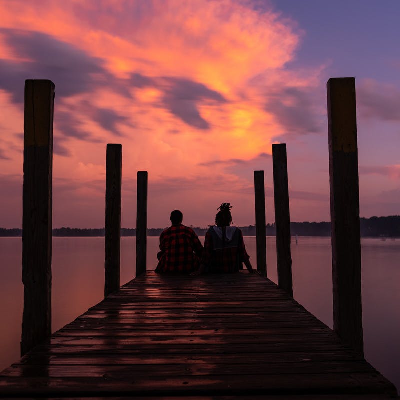Chanel and Brittany Tate sitting on a dock watching the sunset. 