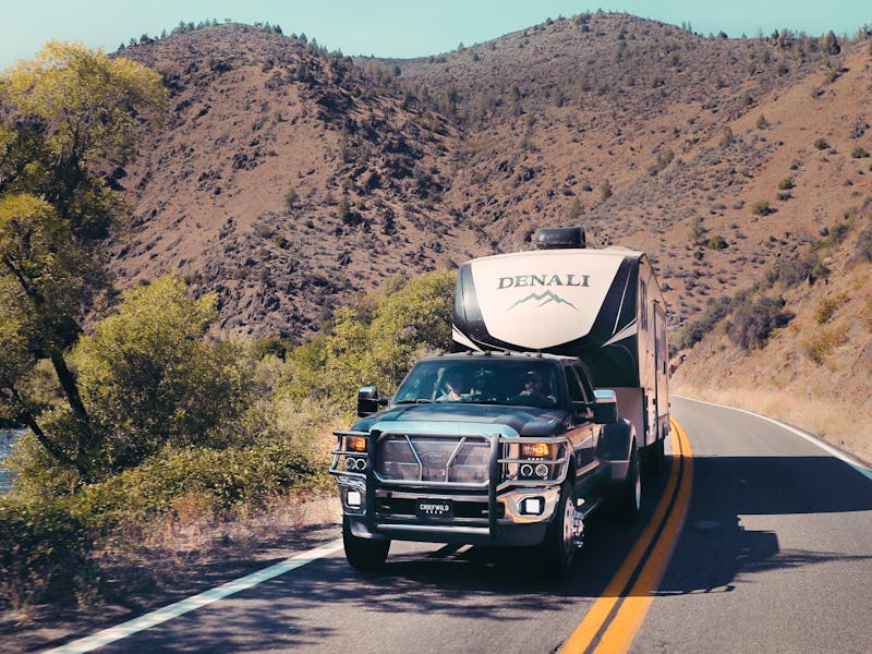 A Dutchmen Denali RV driving on the road.