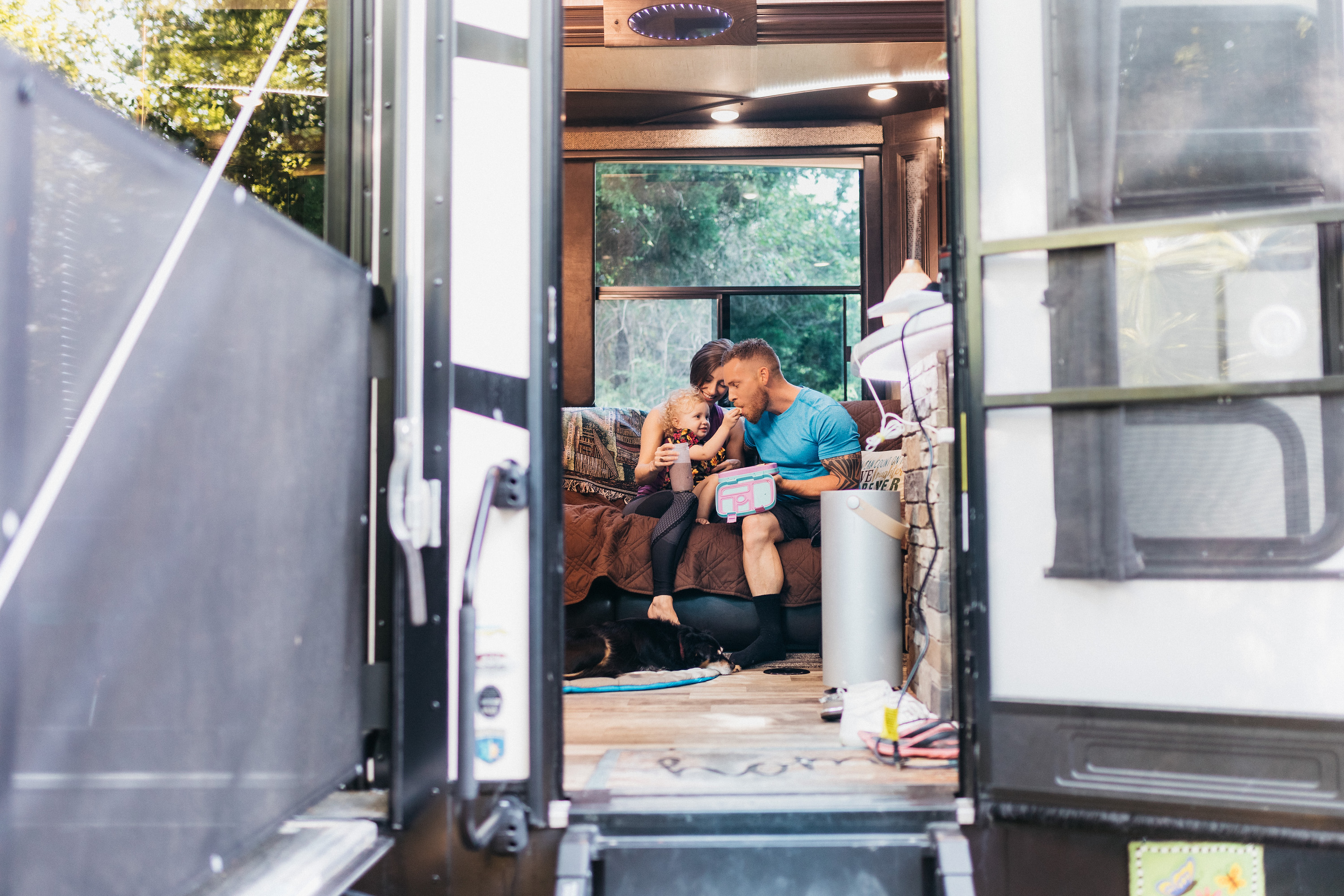 A young family eating snacks together on a couch inside an RV.