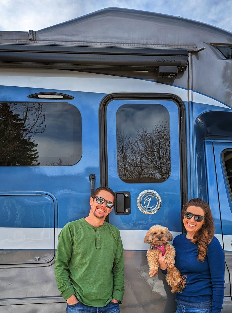Dustin and Sarah Bauer holding a pup in front of their RV