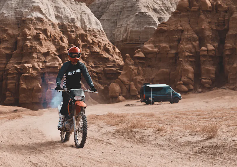 Kalen Thorien riding on a dirt bike away from a camper van