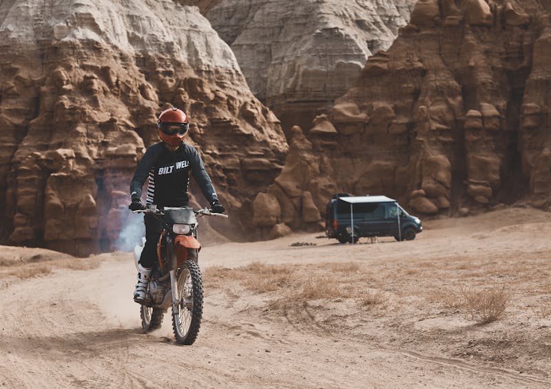 Kalen Thorien riding on a dirt bike away from a camper van
