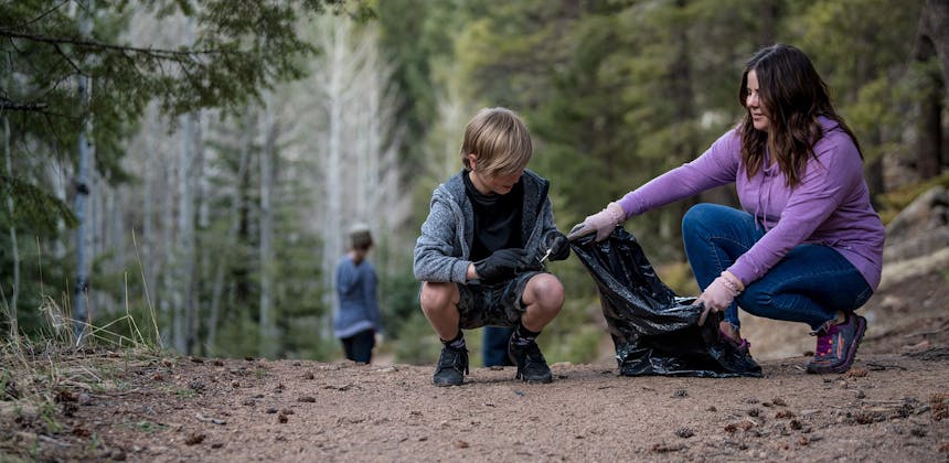 A woman holding a bag of trash for a boy