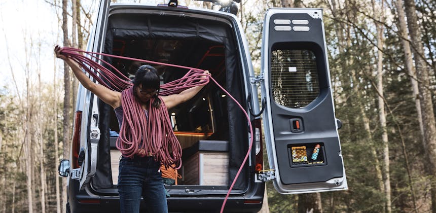 Kathy Karlo prepping climbing gear outside of an Airstream camper van