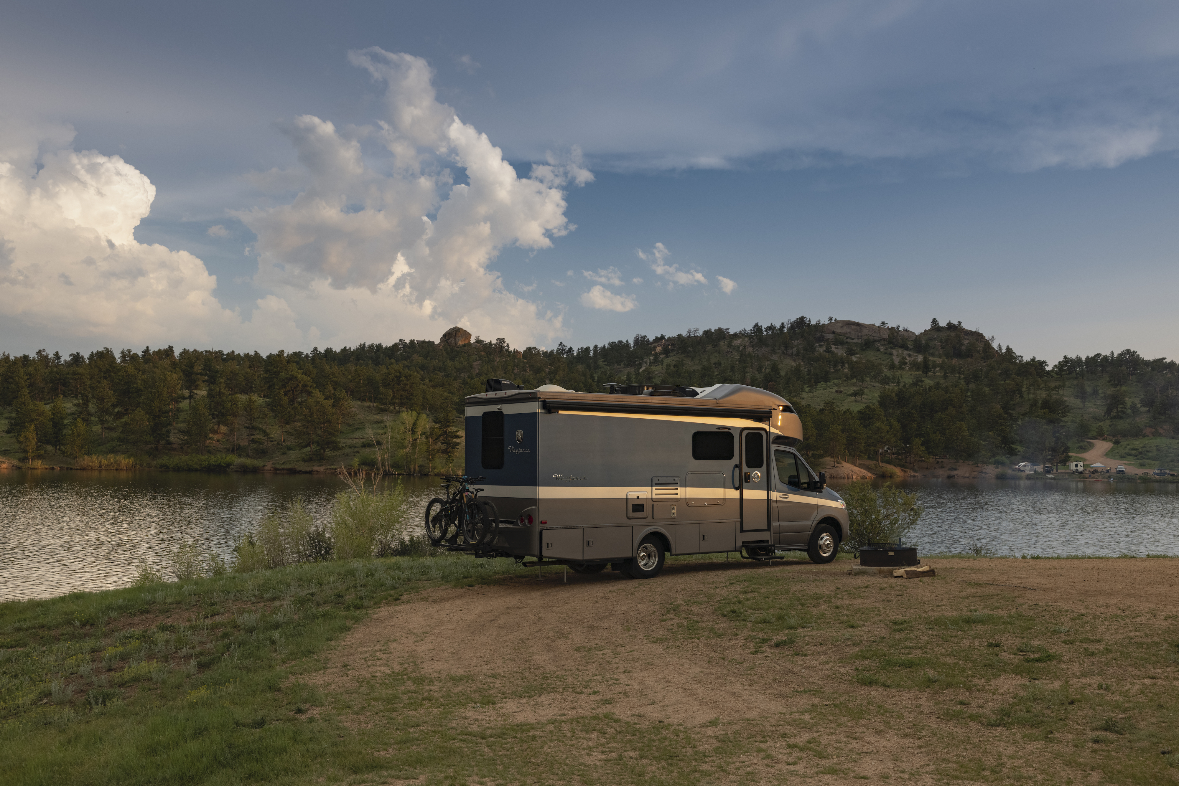 Dustin and Sarah's Tiffin Wayfarer RV parked at a campsite next to a lake
