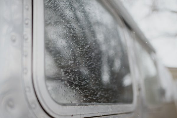 Gray shot, close up of rain and water on the window of an Airstream RV.
