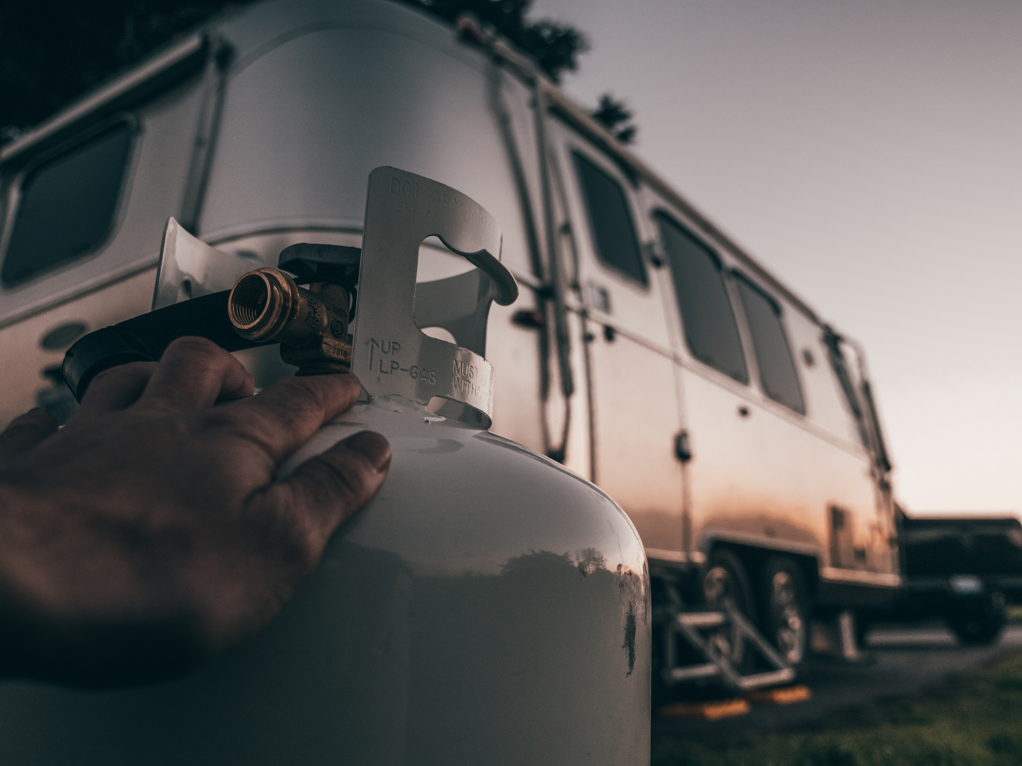 A tank of propane in front of an RV