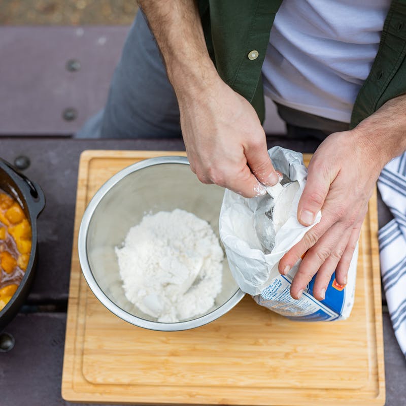 Measuring out flour into a bowl for the cobbler topping.