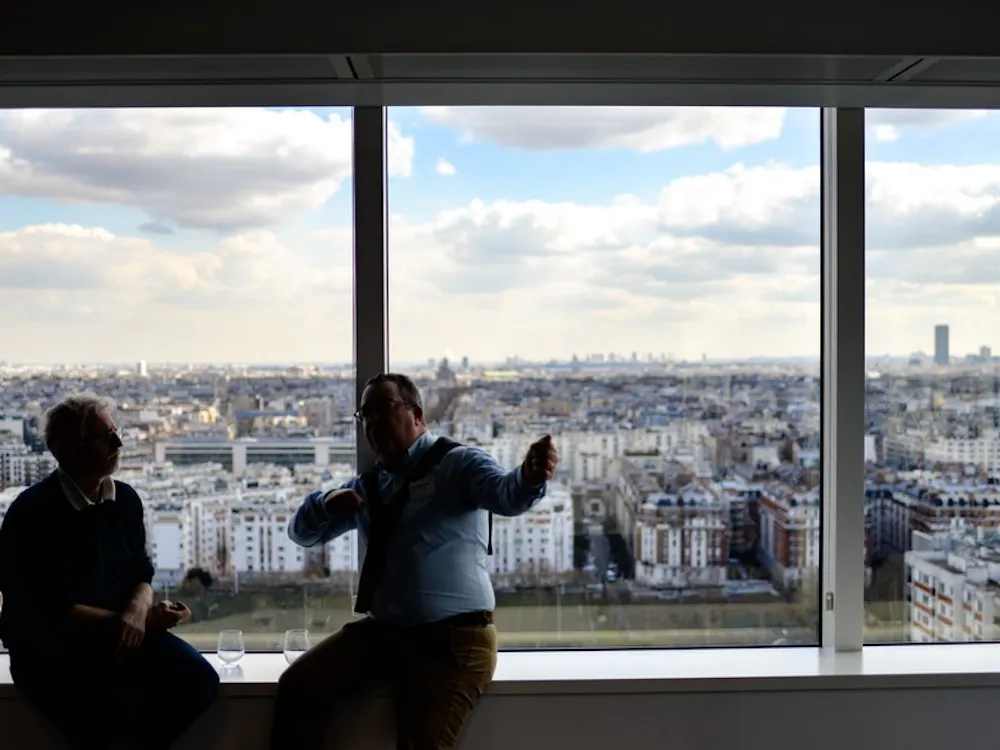 Two men in discussion, sitting in sky scraper building overlooking city