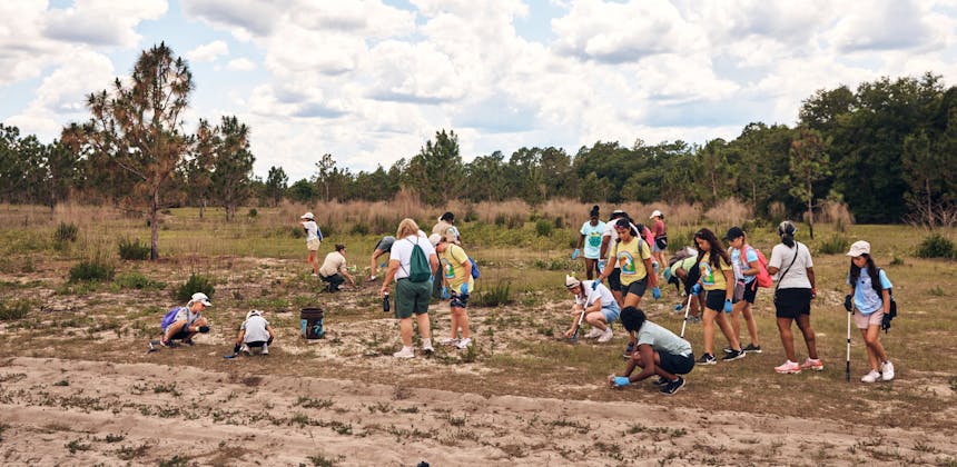 A group of girl scouts and volunteers at a park cleanup event