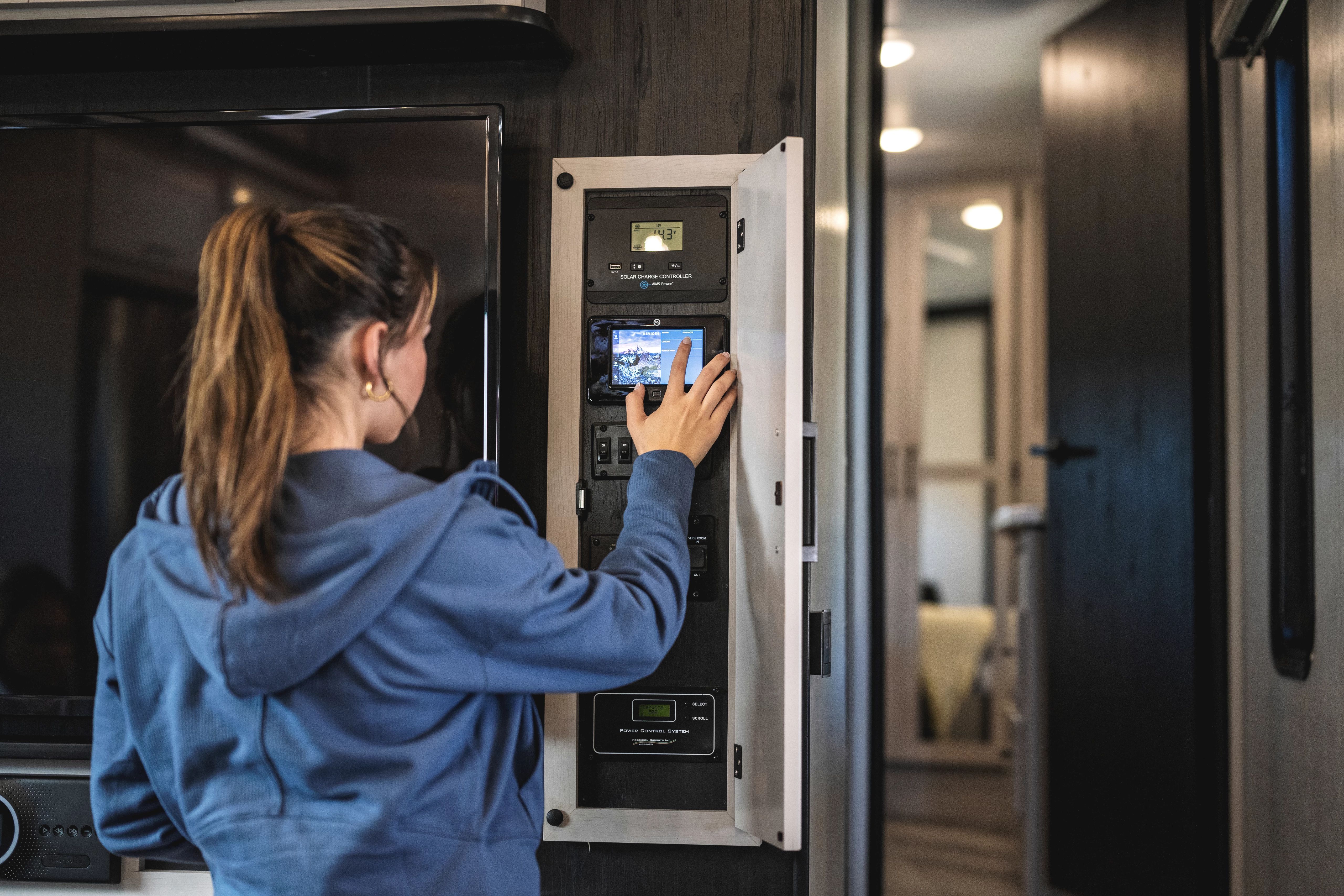 A woman looks at a control panel inside a fifth wheel RV