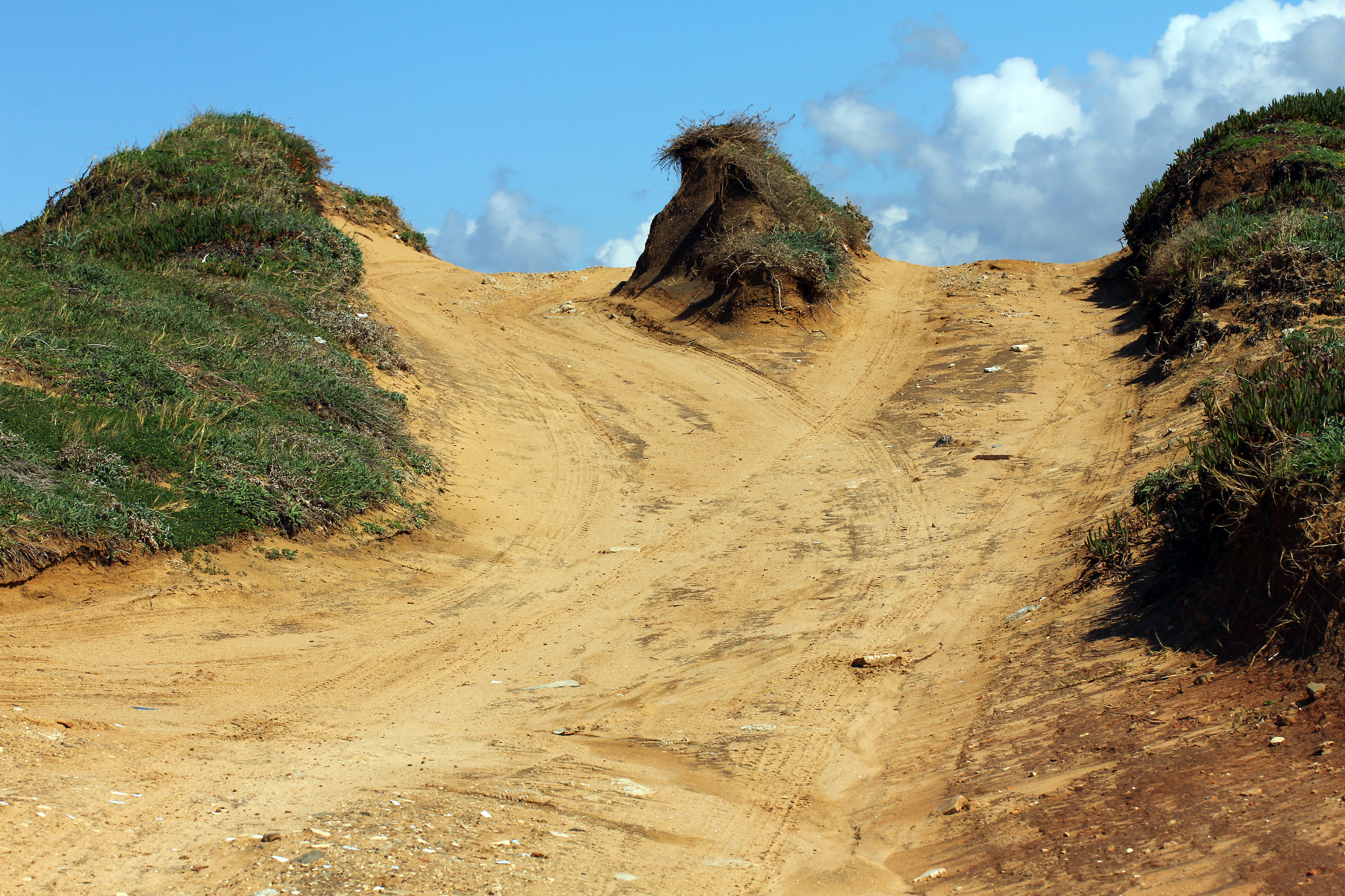 Sand trails converge over a hilltop. 