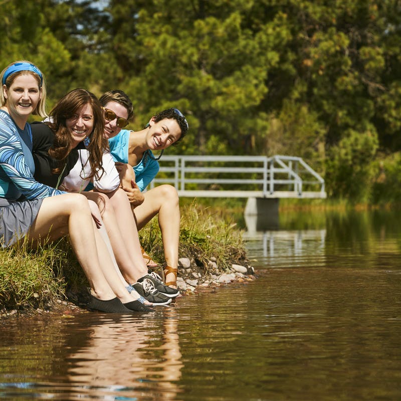 A group of participants rest their feet in the water of the Blackfoot River.