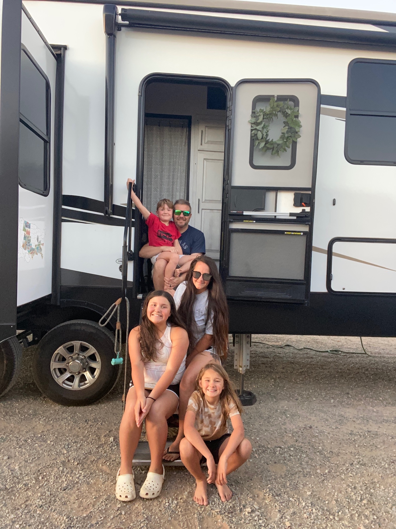 DARREN & AMANDA BONE's family sitting on the steps of their RV for a picture