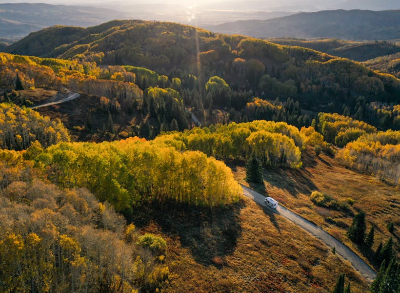 An RV driving through fall foliage