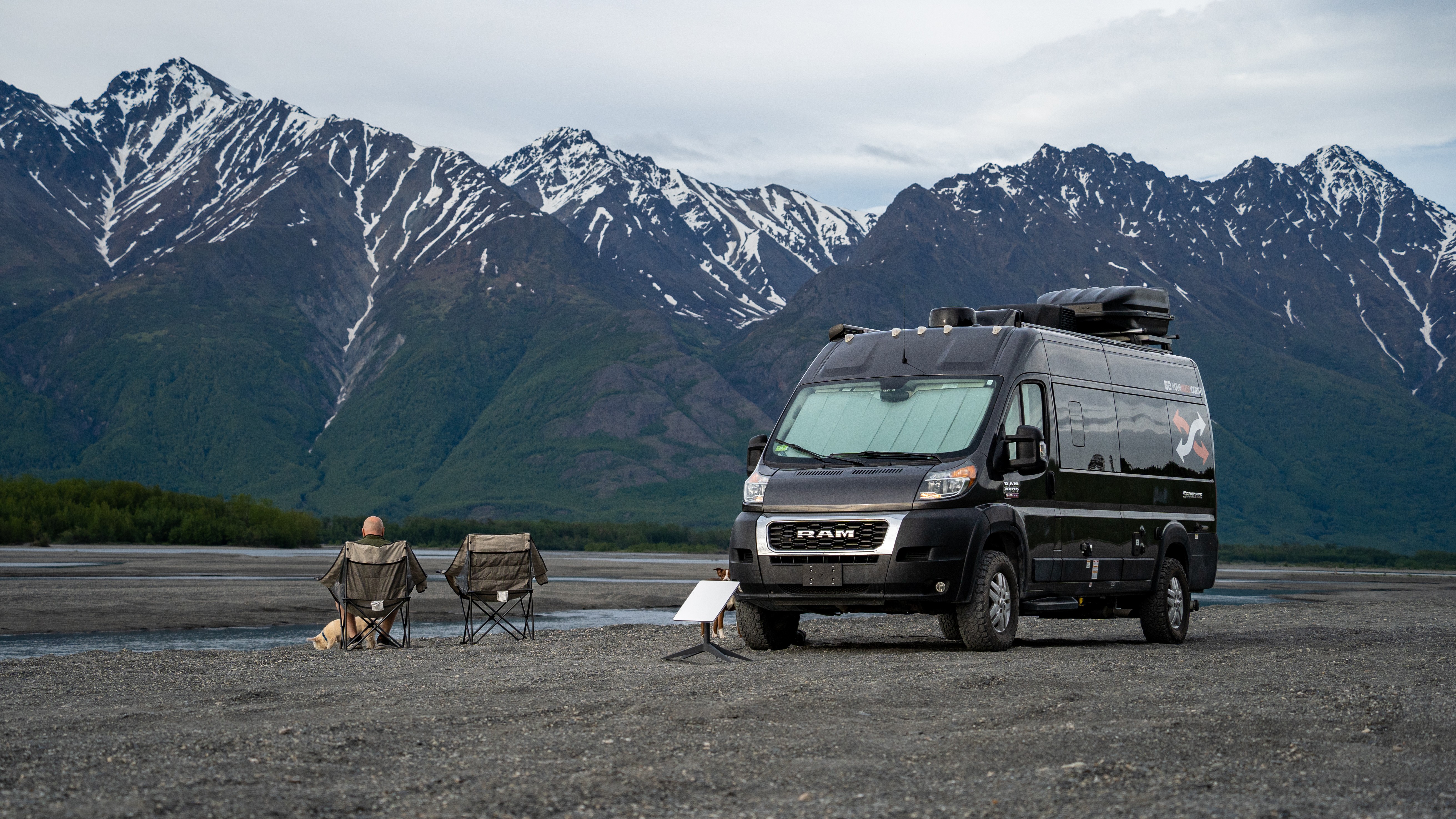 Gabe and Rocio Rivero sitting in front of their RV with a starlink by a mountain camping location