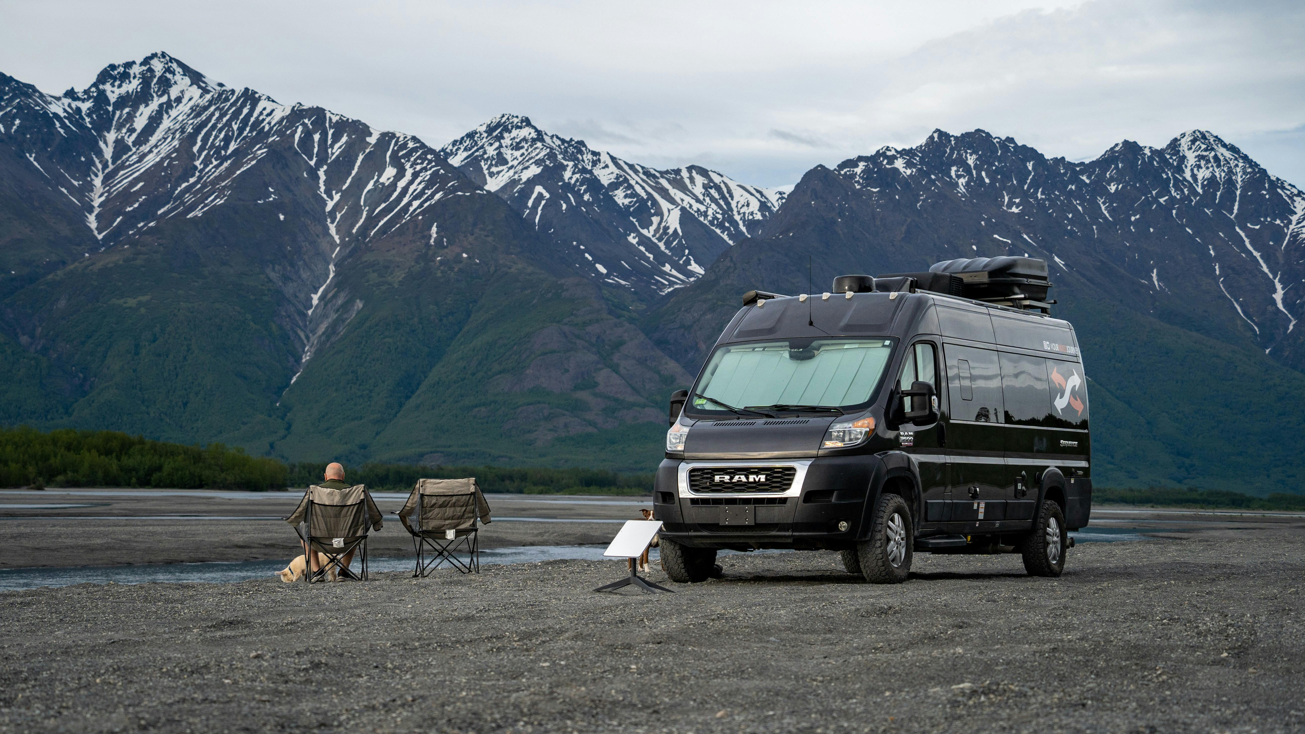 Gabe and Rocio Rivero sitting in front of their RV with a starlink by a mountain camping location