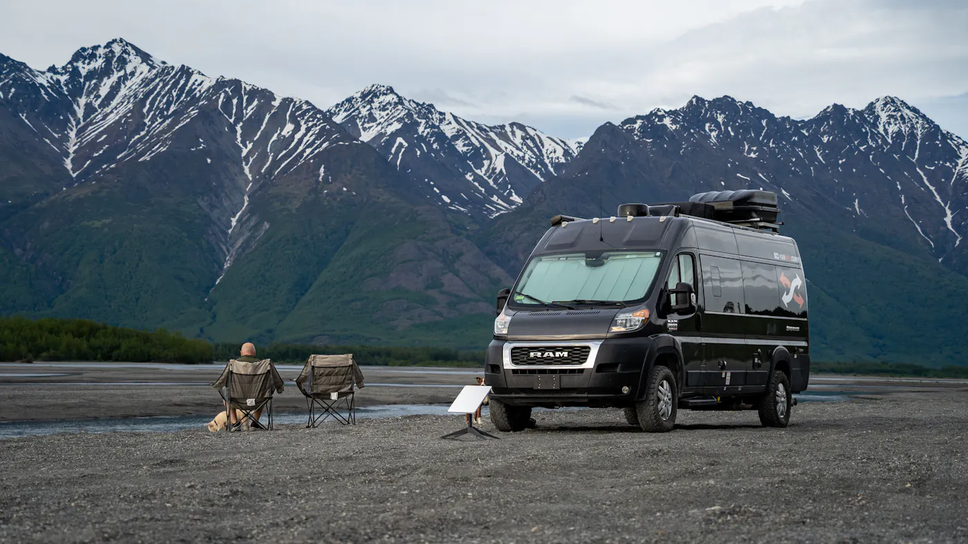 Gabe and Rocio Rivero sitting in front of their RV with a starlink by a mountain camping location