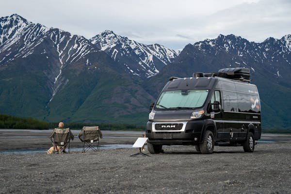 Gabe and Rocio Rivero sitting in front of their RV with a starlink by a mountain camping location