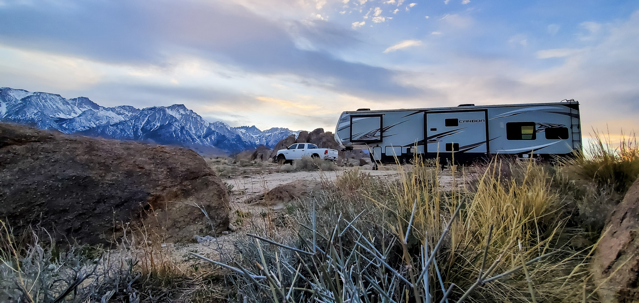 A toy hauler RV parked at the foot of snow covered mountains.