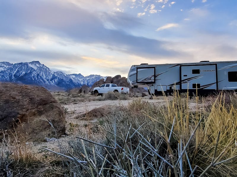 A toy hauler RV parked at the foot of snow covered mountains.