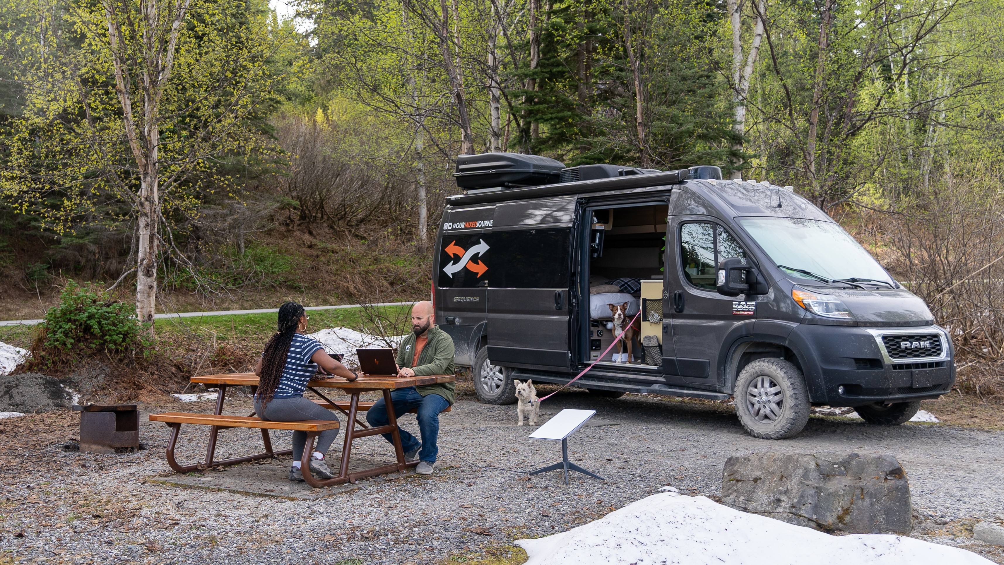 Gabe and Rocio Rivero working on their laptops outside of their 2021 Thor Motor Coach Sequence 20L