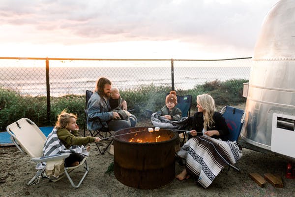 Amber Thrane and her family roasting marshmallows over a fire by an Airstream Travel Trailer RV