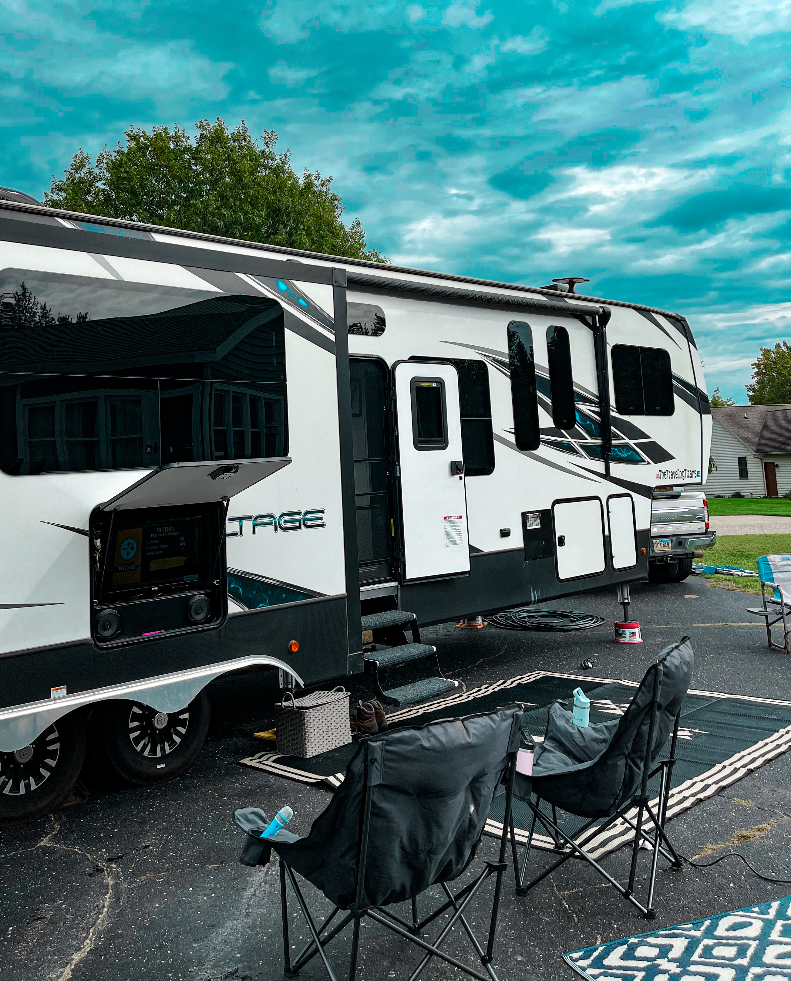 SAMANTHA BADERSCHNEIDER AND BLAKE EDMUNDS' Dutchmen Voltage parked at a campsite with camp chairs in front of it