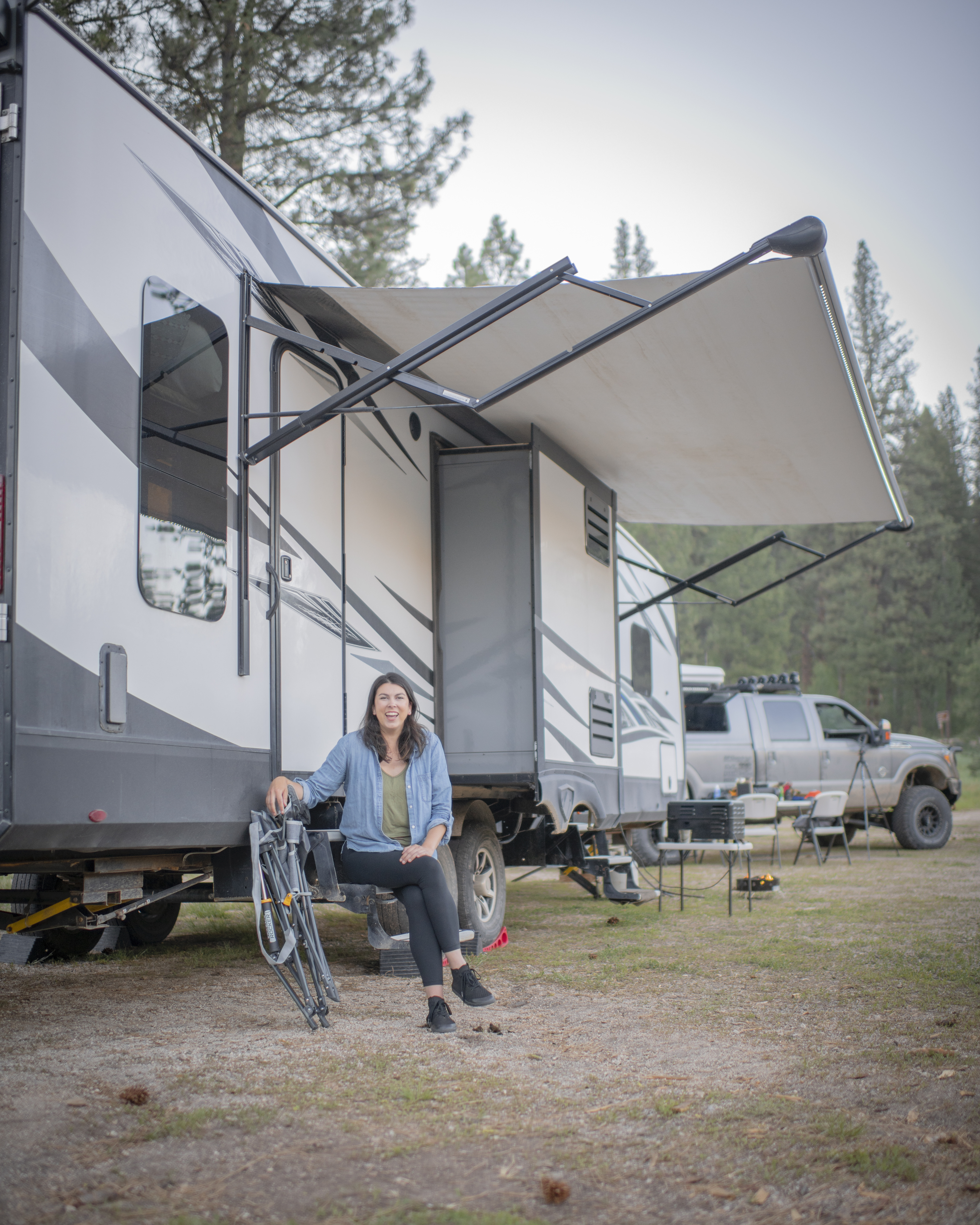 Chelsea Day smiling while sitting on the steps of her Highland Ridge RV