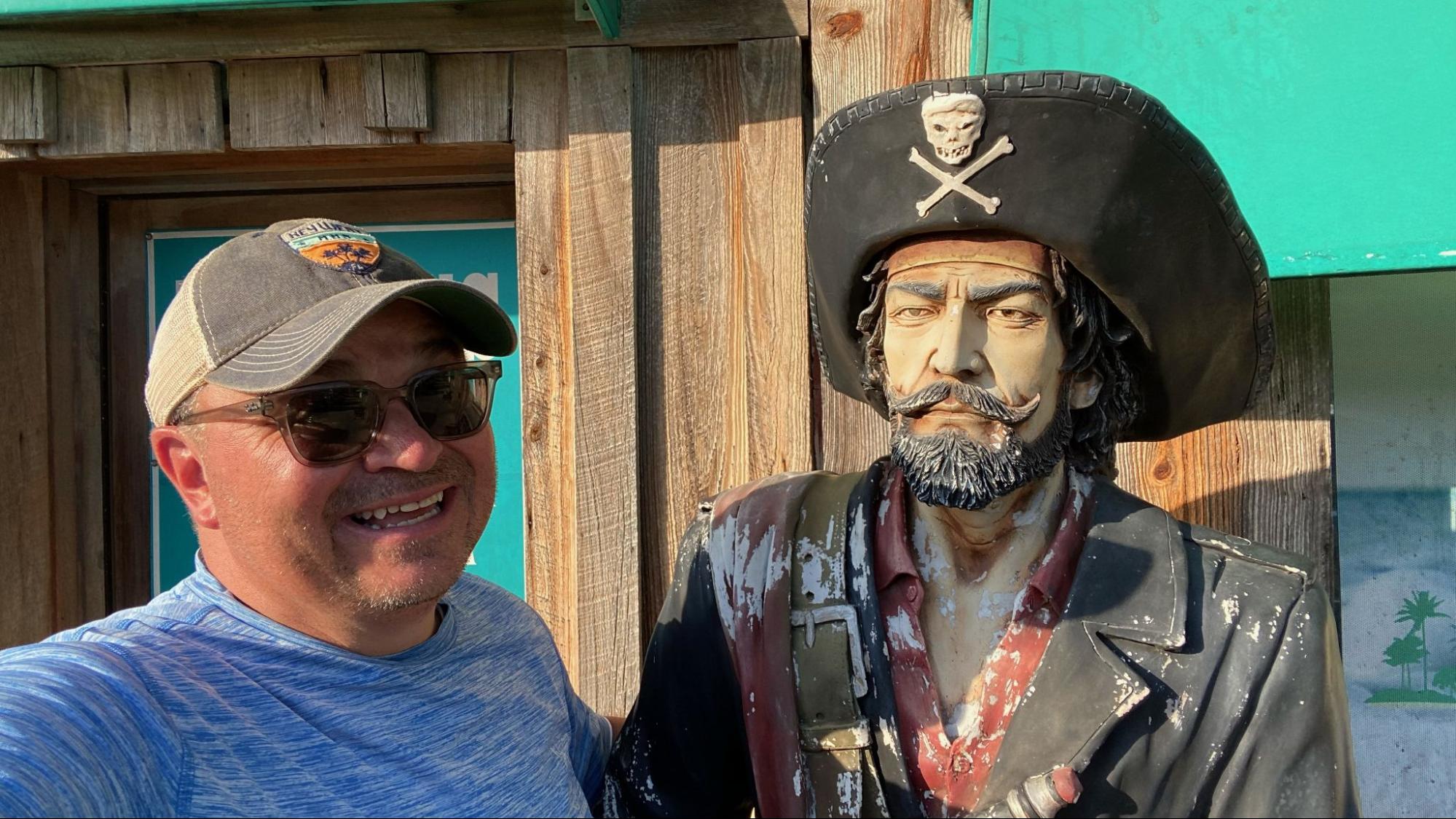 Michael Dunagan takes a photo with a wooden pirate.