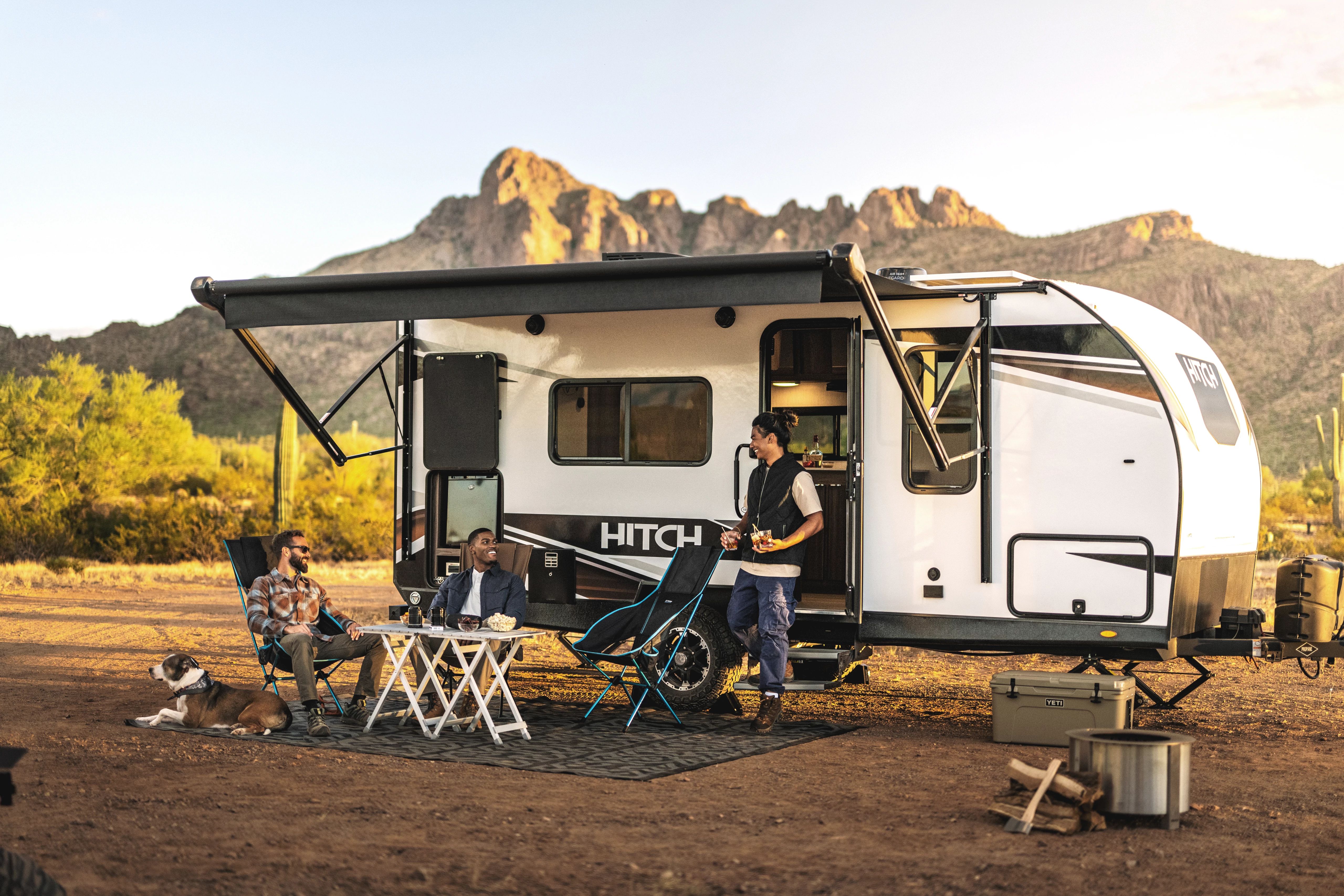 Three men relax outside of a Hitch Lightweight Travel Trailer 