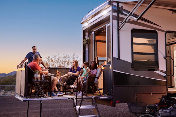 Robin and Warren's family sit on the patio of their Keystone Fuzion at dusk.