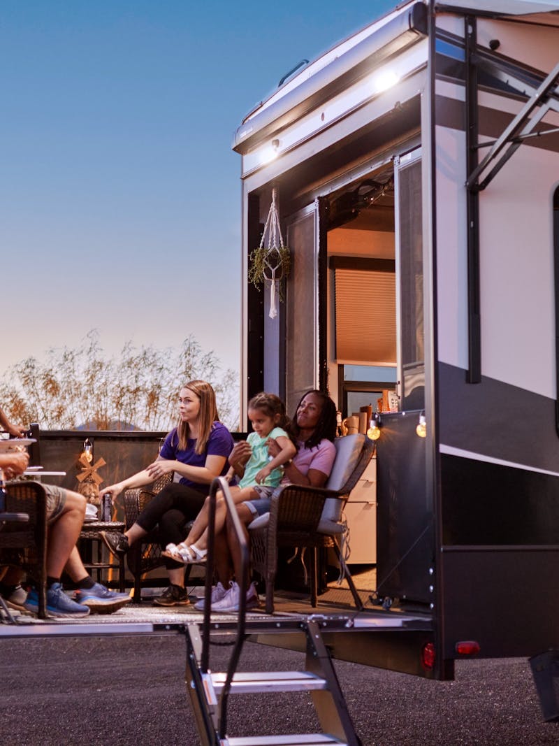 Robin and Warren's family sit on the patio of their Keystone Fuzion at dusk.