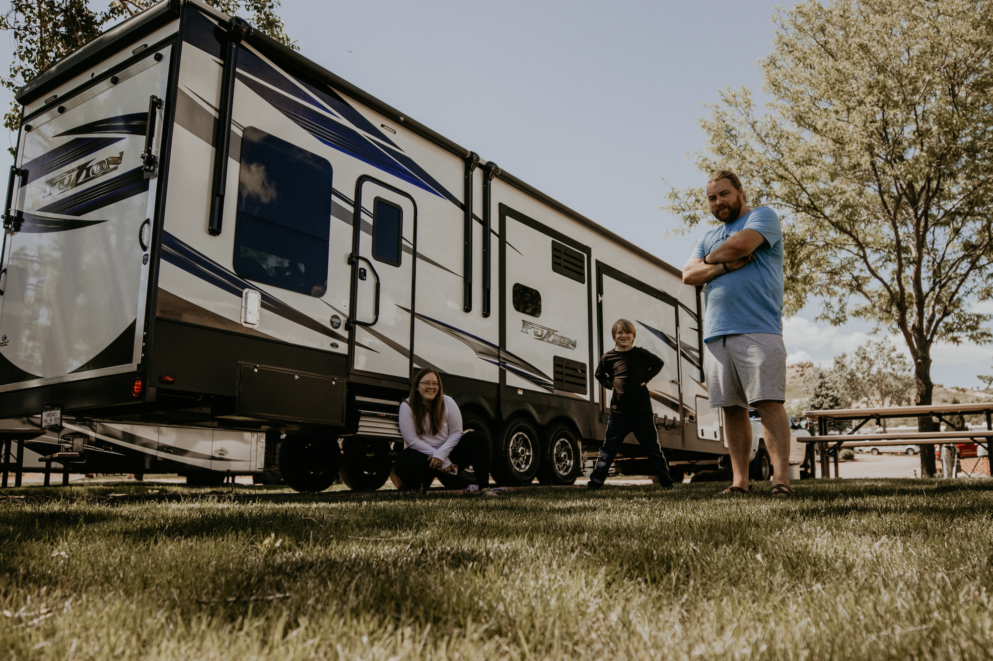 A family standing outside their Toy Hauler RV in the grass. 
