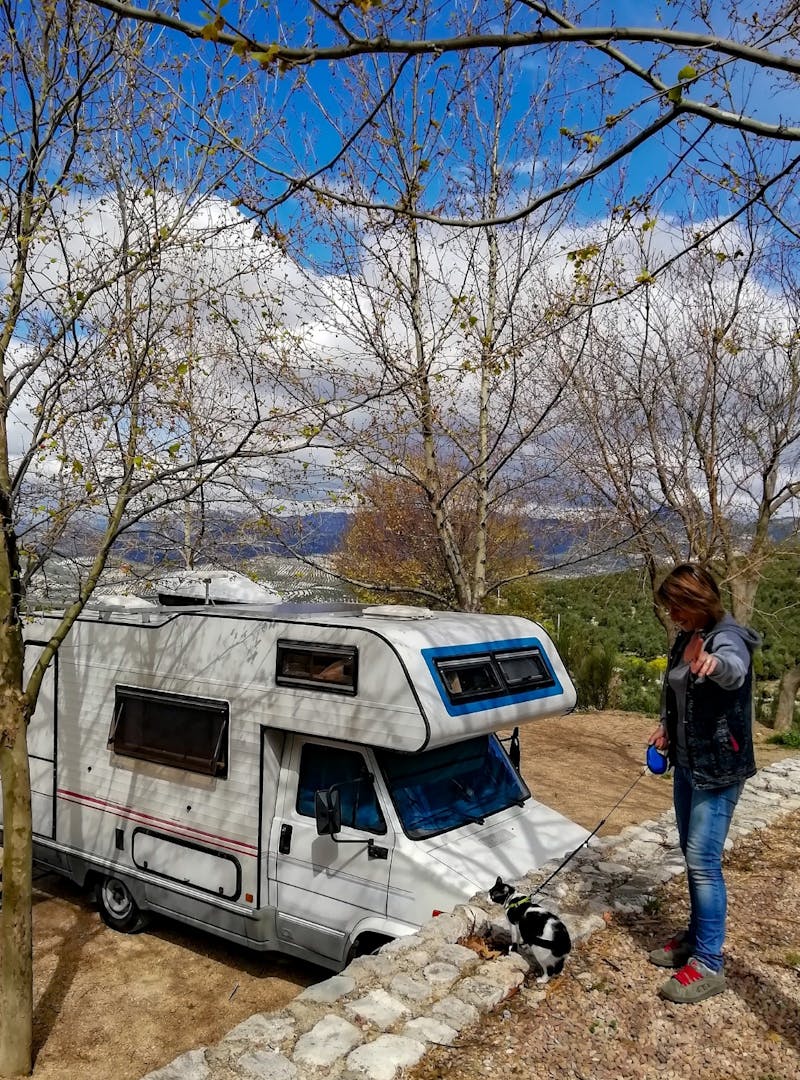 Chiara taking her cat for a walk on a leash with the RV in the background.